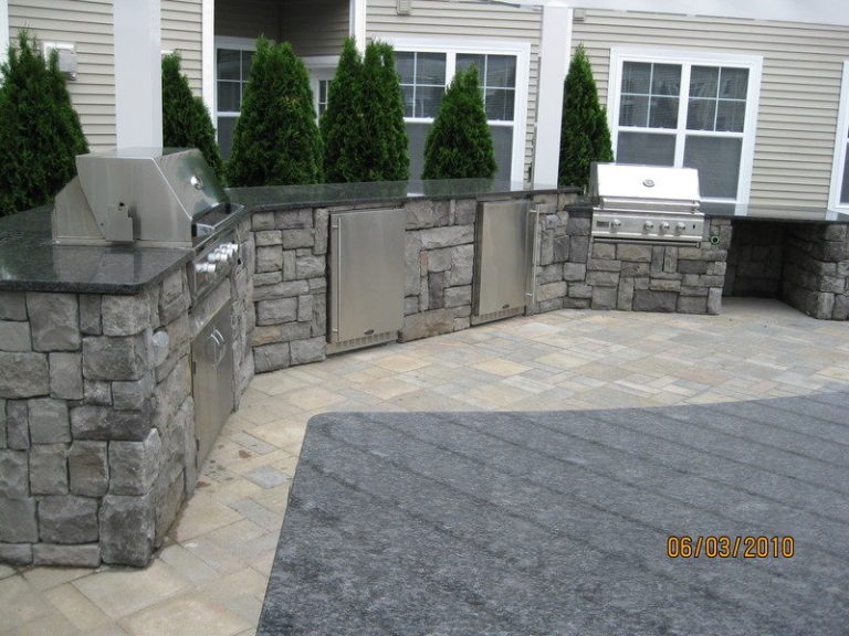 Gray stone-veneer outdoor kitchen with two built-in grills and granite counters