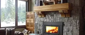 Stone fireplace with wood-burning insert, wood mantel, and built-in cabinet in a living room