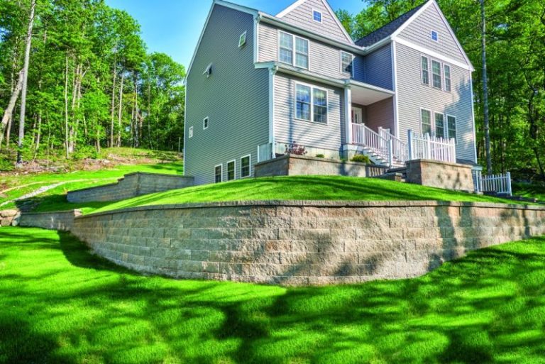 Curved tan retaining wall around a raised lawn in front of a house