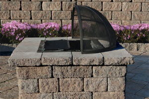 Square stacked-stone fire pit table with the spark screen lid open