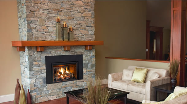 Stacked stone fireplace with a wood mantel and square black gas insert in an open living room.