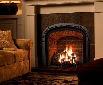 White mantel surround with an arched black gas insert and slate tile, lit in a cozy living room.