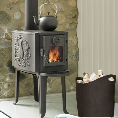 Small black cast-iron wood stove with a decorative door panel and a kettle on top