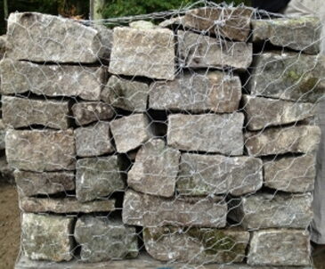 Pallet of gray rectangular wall stone blocks wrapped in wire mesh.