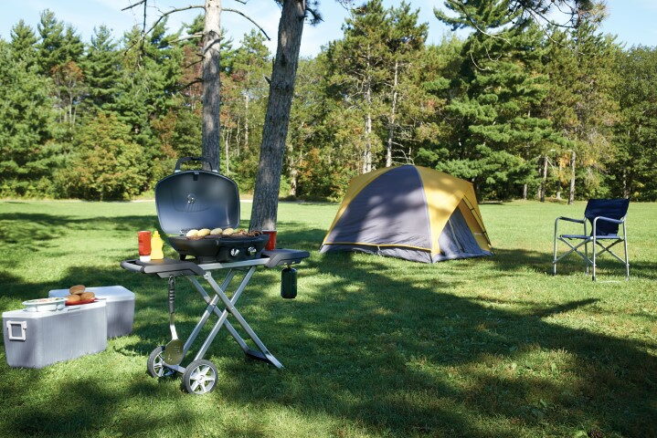 Portable black Napoleon gas grill on a folding cart at a campsite