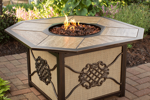 Octagonal tile-top gas fire table with woven side panels in a garden setting