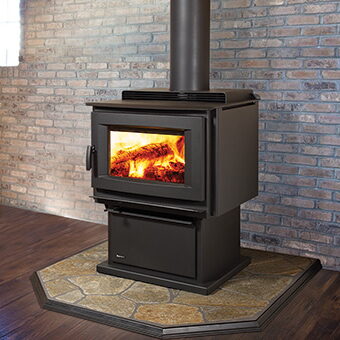 Black freestanding wood stove on an octagonal stone hearth against a brick wall