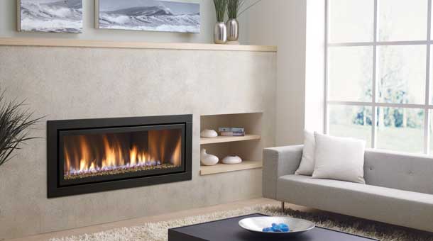 Modern linear gas fireplace with black frame and glass media in a light stone wall.