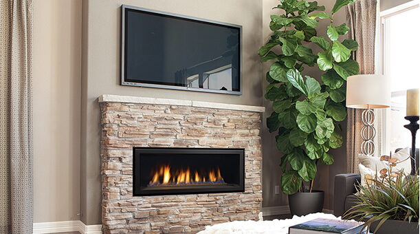 Linear stacked-stone gas fireplace below a wall-mounted TV in a living room