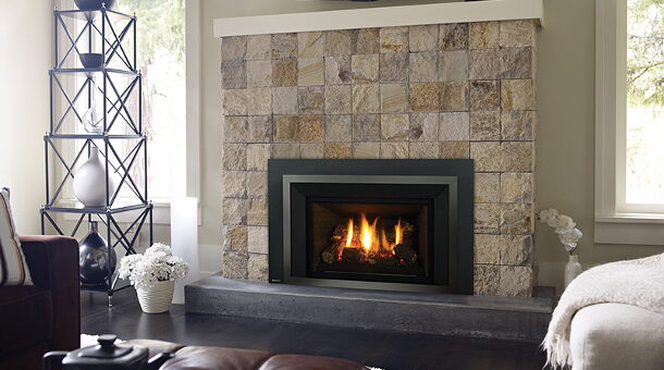 Stacked stone fireplace surround around a black-framed gas fireplace insert