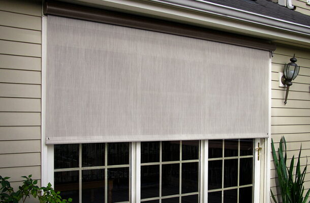 Retractable screen shade mounted above a window on a house