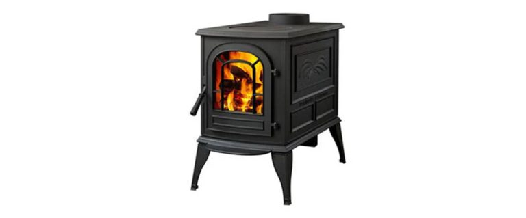 Black cast-iron wood stove with an arched door and a decorative leaf panel on legs.