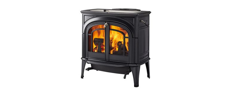 Black Vermont Castings wood-burning stove with an arched glass door and a lit fire