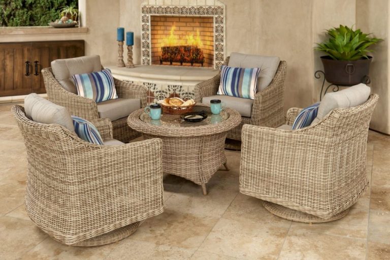 Four tan wicker swivel chairs with blue striped pillows around a round table near a tiled fireplace.