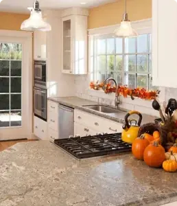 White kitchen with granite countertop, gas cooktop, farmhouse sink, and fall pumpkin decor