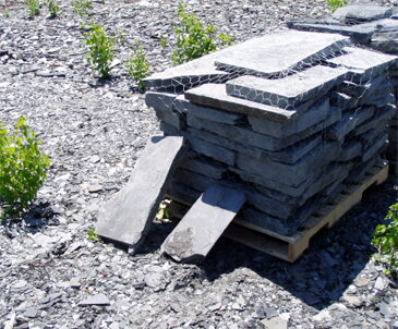 Pallet of flat dark gray slate stone slabs wire-wrapped in a stone yard.