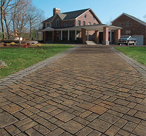 Brick-paver driveway leading to a brick colonial home.