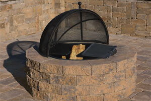Round stacked-stone fire pit with a domed mesh spark screen cover
